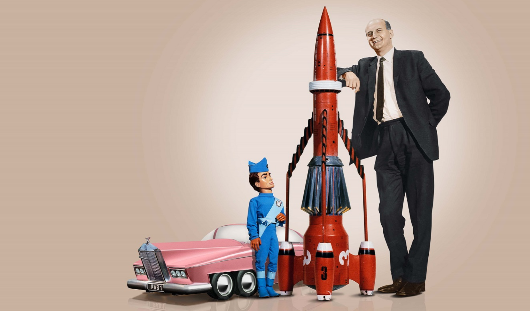 Gerry Anderson leans on a large model of Thunderbird 3 observed by one of his puppet creations Scott Tracy
